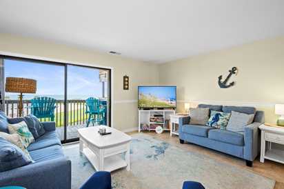 Unwind in your coastal-inspired living room, where sliding glass doors reveal a private balcony with serene views. Comfy seating and beach decor set the perfect mood for relaxing after a day exploring the shore.